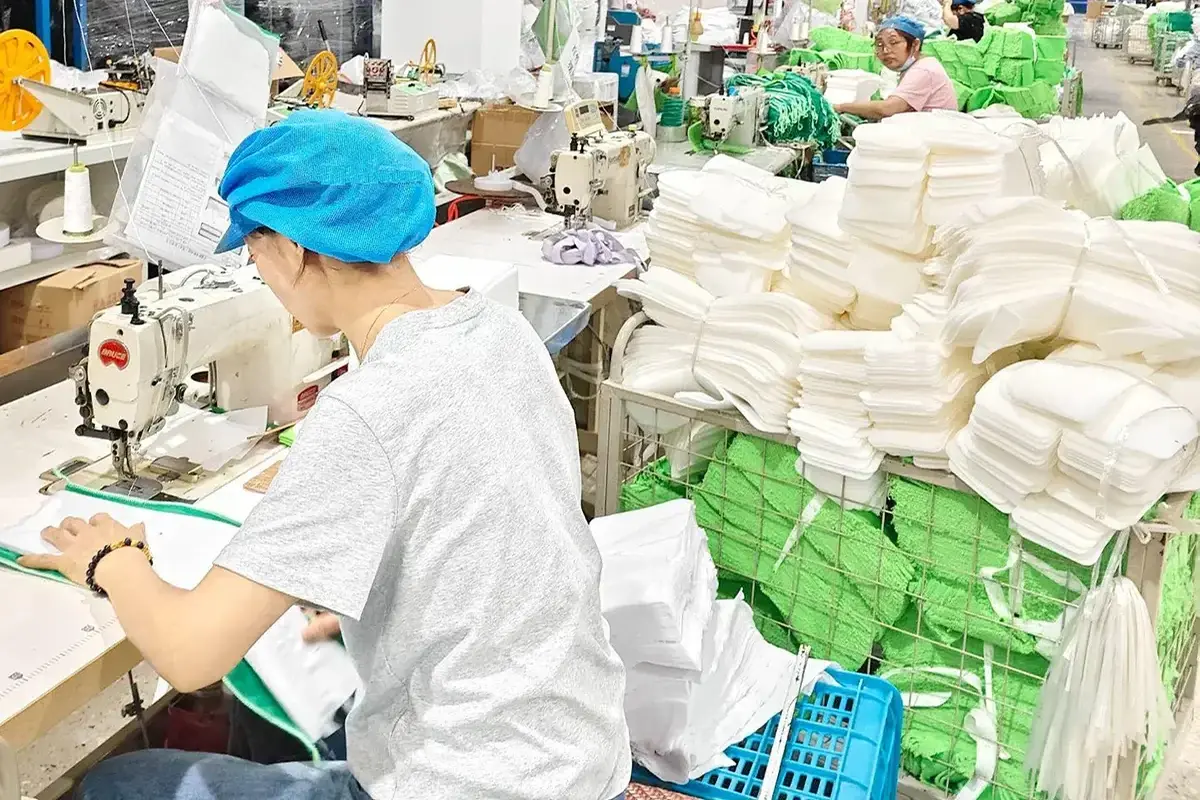 Factory team sewing and finishing a bulk order of white hotel and spa towels