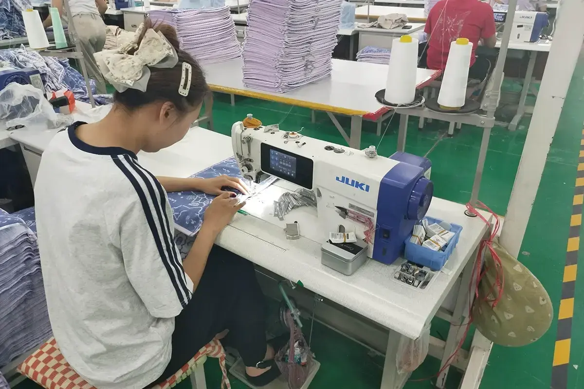 Factory operator stitching and checking purple gym towels during production