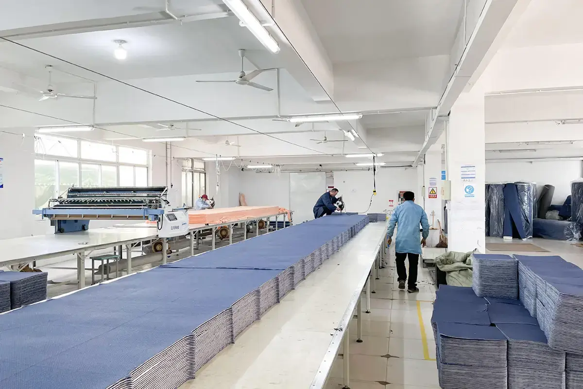 Workers handling bulk textile panels on a long production line inside the towel factory