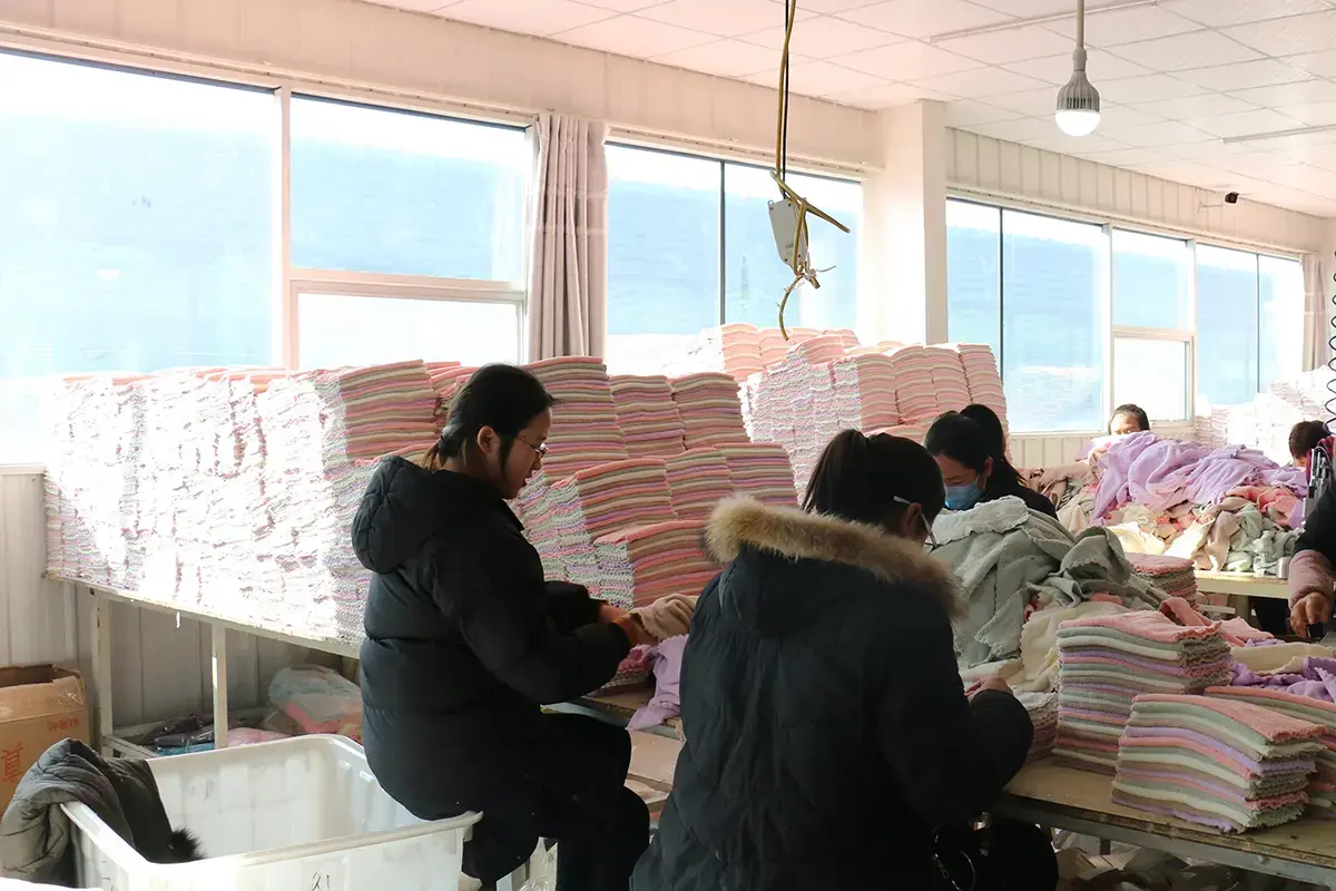 Workers sorting and inspecting stacks of microfiber towels during final quality checks