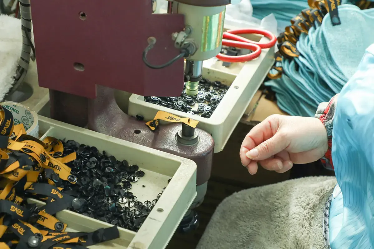 Worker positioning a towel component under an attachment machine