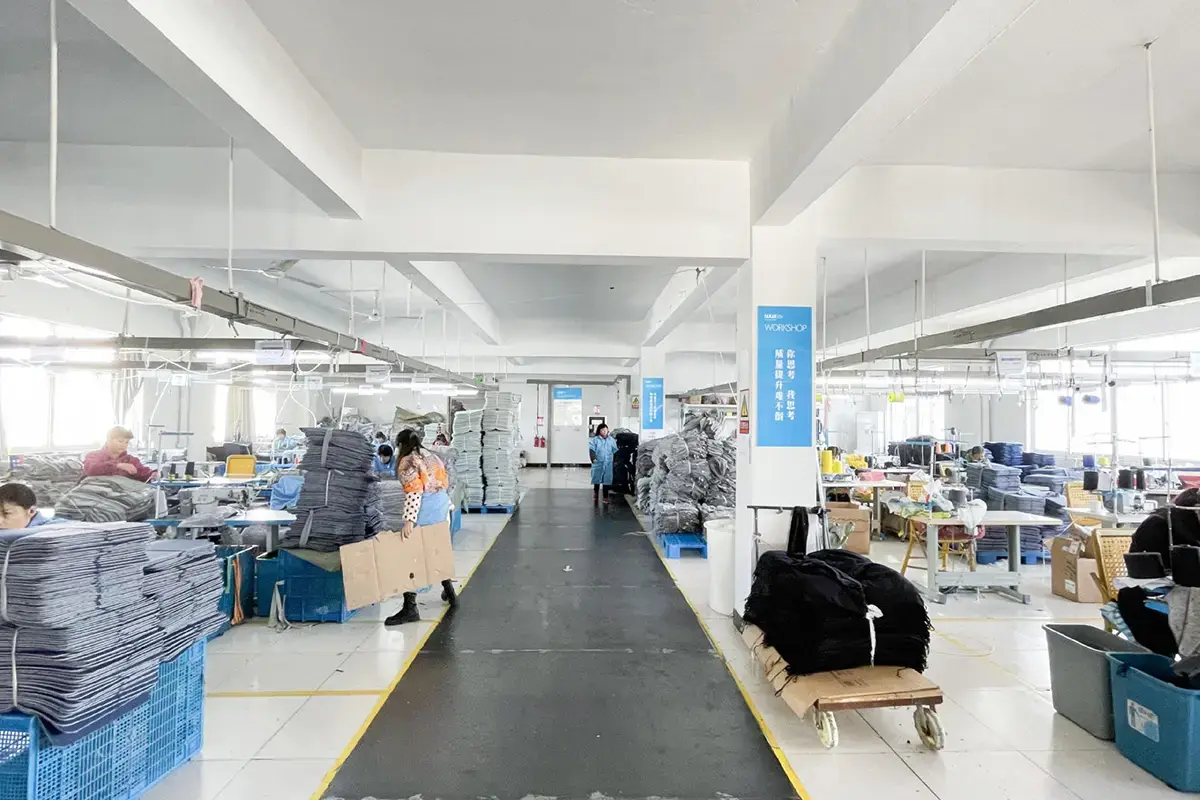 Wide factory aisle showing organized work areas, finished stacks, and production flow